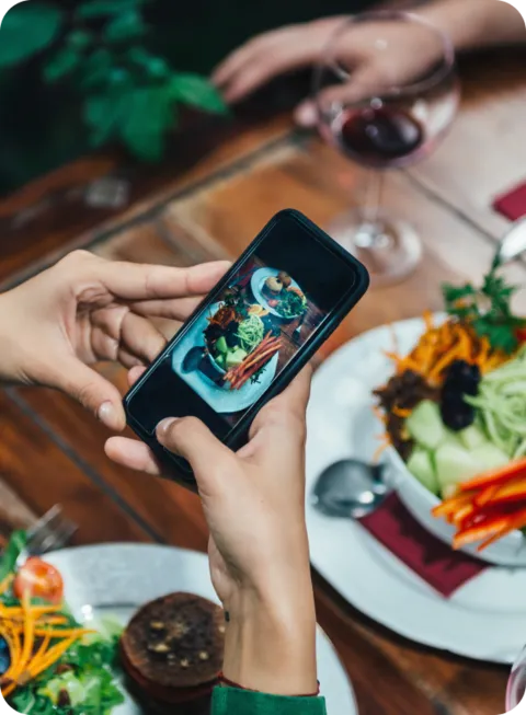 Photo of someone taking a photo of their food on their phone